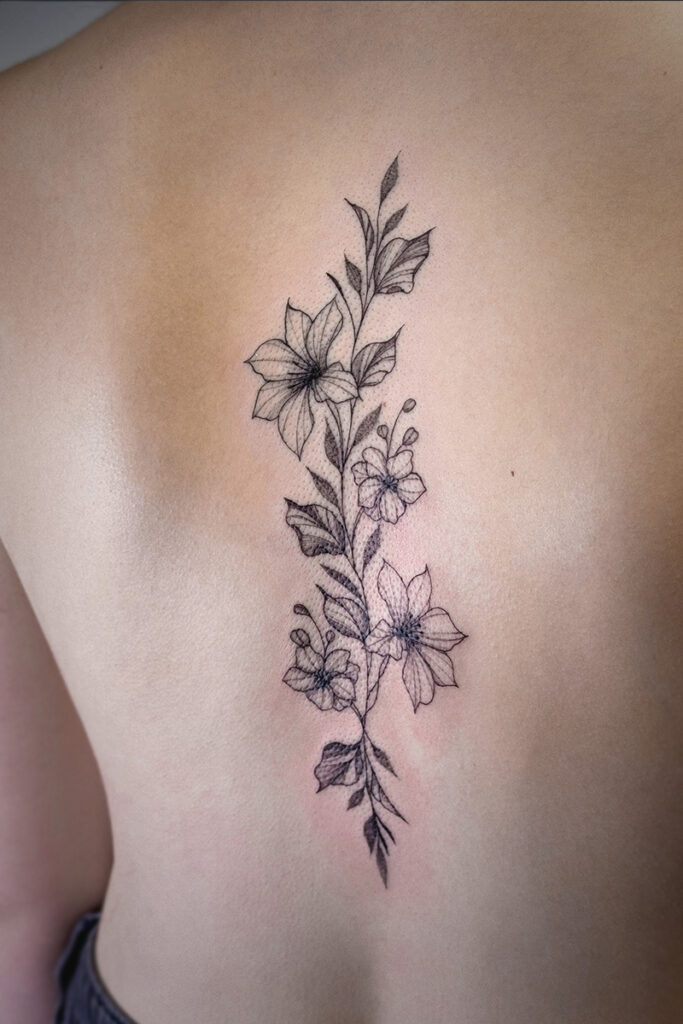 Aesthetic Tattoo Art| Fine line tattoo of a stem of flowers on the client's back